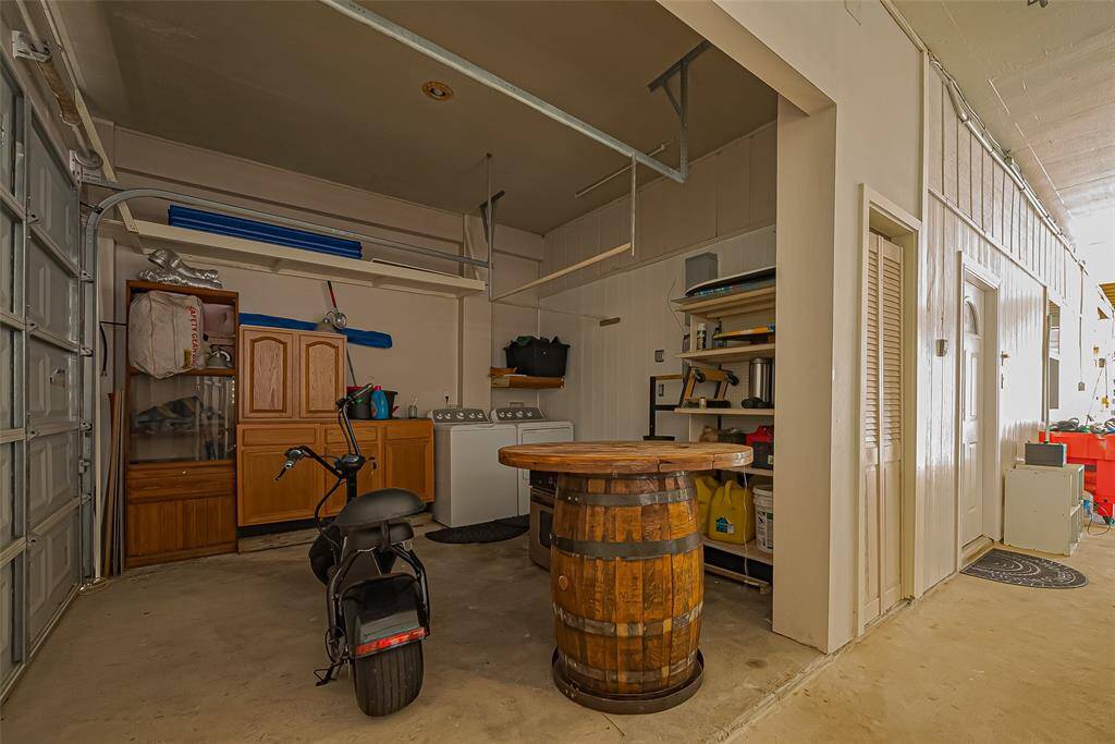 The garage features ample storage with cabinets and shelving, a washer and dryer, and an extra space for a small vehicle or scooter.