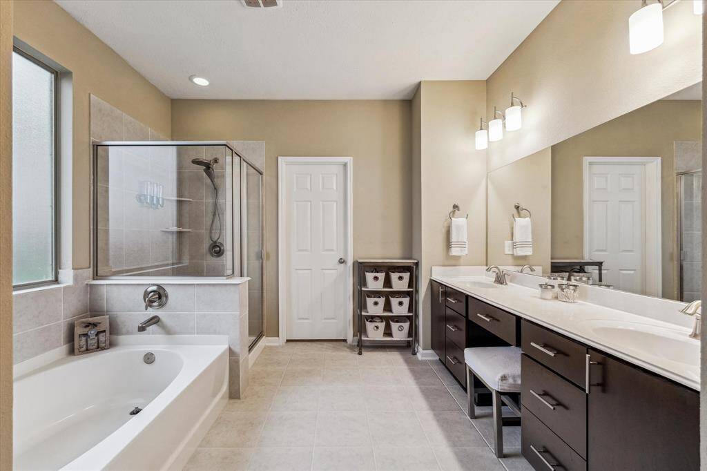 The luxuriously appointed primary bath offers a spacious, spa-like retreat, complete with generous countertop space, a large garden tub, and a separate stand-up shower.
