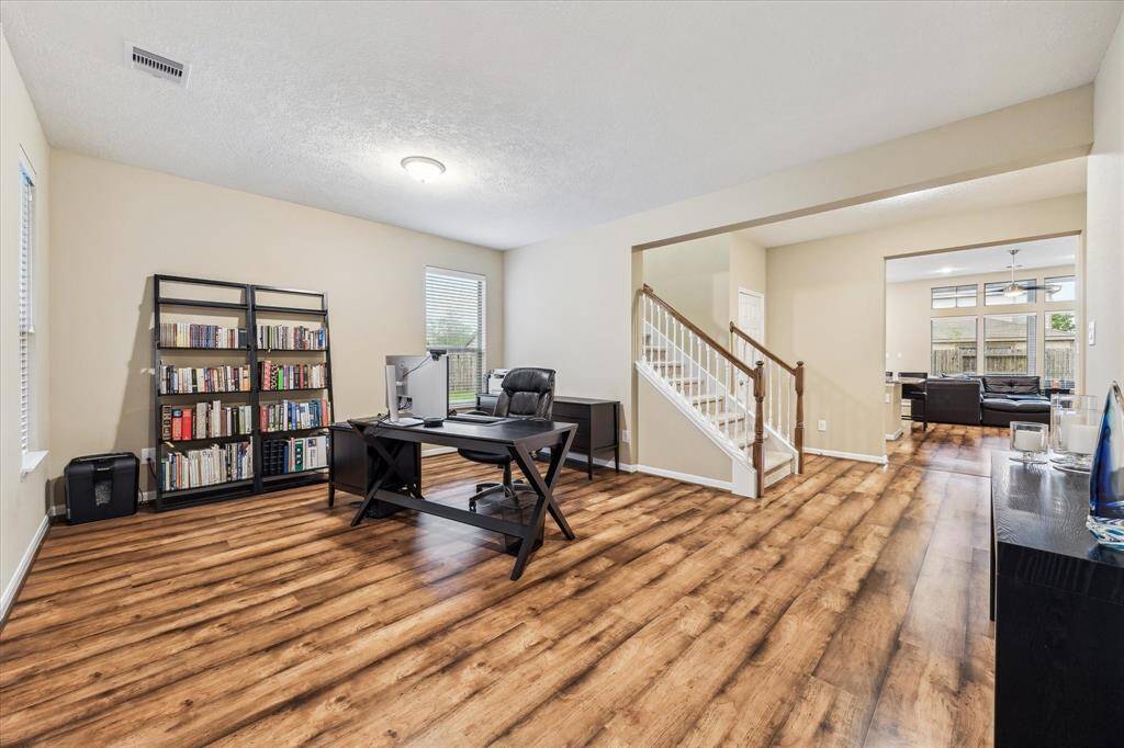 As you step inside, upgraded wood floors and soaring ceilings set the tone in the spacious formal dining room—currently styled as a functional home office.