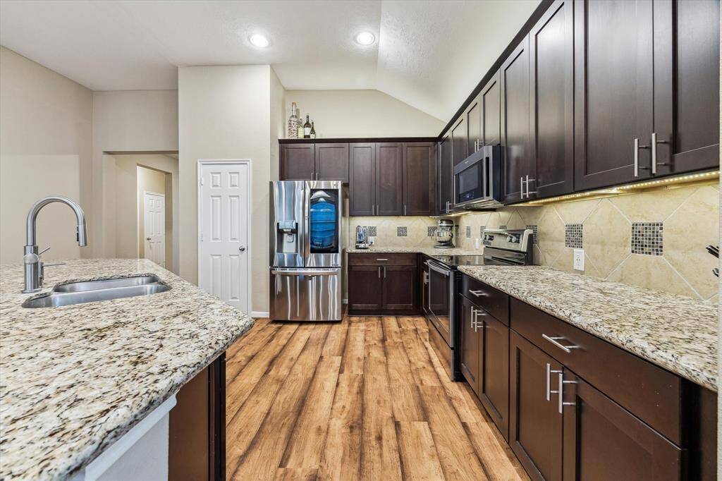 The beautifully upgated kitchen features endless countertops and sleek cabinetry that stretch across the space. A large island adds even more room for cooking, serving, and entertaining. Builder upgrades include modern 42" cabinets, stylish countertops, stainless steel appliances, and a designer tile backsplash.