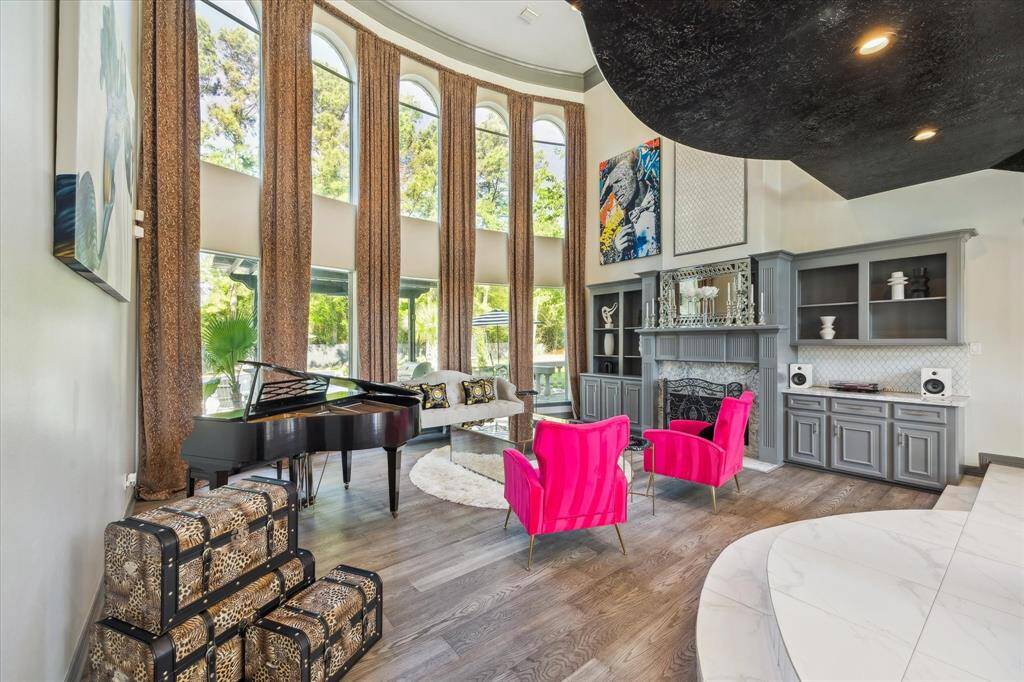 This elegant living room features high ceilings with large arched windows that flood the space with natural light. It includes a classic fireplace, creating a stylish and inviting atmosphere. The built-in shelves and decorative accents add to the room's sophistication.