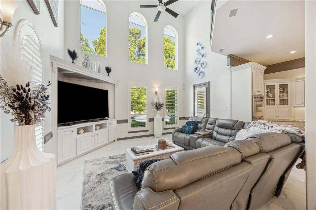 Spacious living room with high ceilings and large windows, offering plenty of natural light. The open layout connects to a modern kitchen, perfect for entertaining.