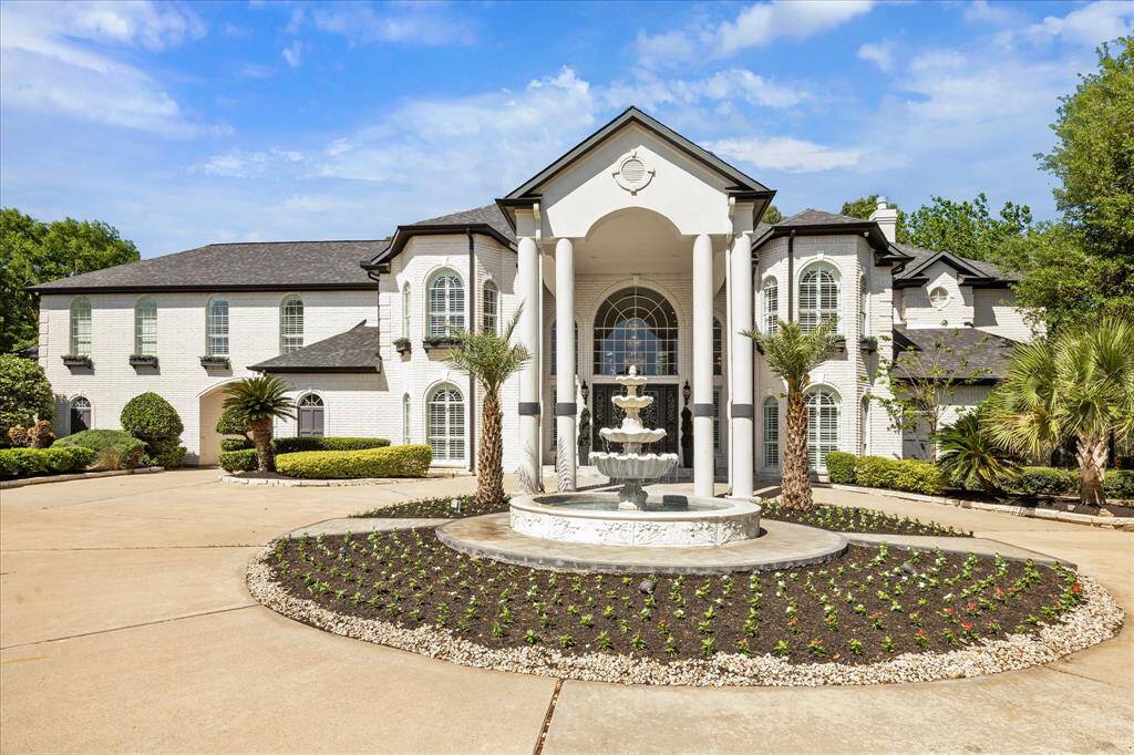 The exterior is accented with manicured landscaping and tall windows, providing a luxurious and welcoming curb appeal.