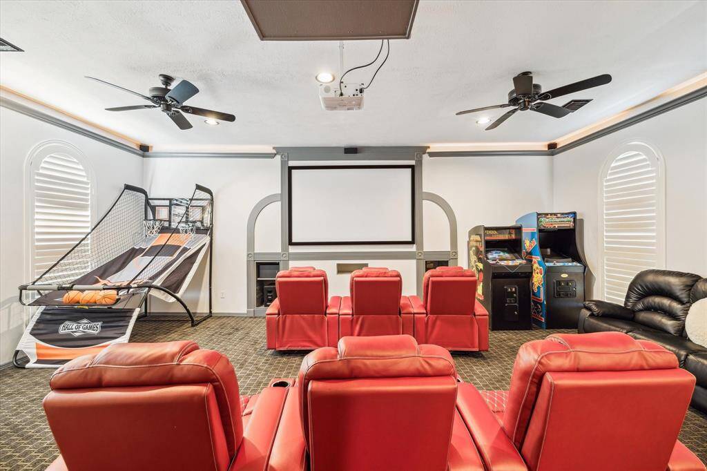 This spacious game room area features a high vaulted ceiling with recessed lighting and a ceiling fan. It includes a built-in entertainment center, hardwood floors and large windows provide a warm, inviting atmosphere, with doors that lead to your own balcony overlooking the backyard oasis.