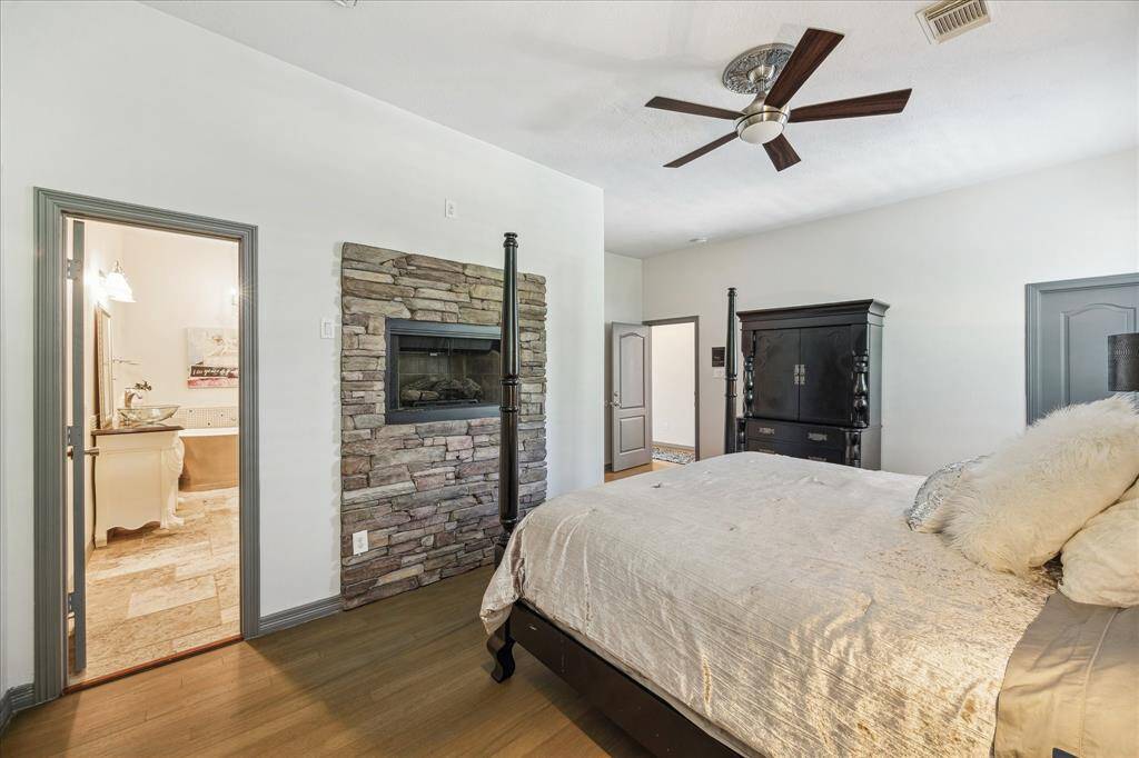 This bedroom features a modern design with a vaulted ceiling, large arched windows with shutters, and ample natural light. A full bathroom is also connected to this bedroom.