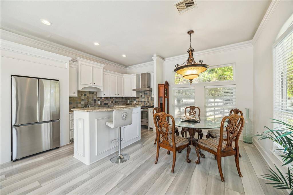 Bright and inviting living room with neutral tones, featuring a ceiling fan, large windows for natural light, and cozy seating. The space is adjacent to a modern bathroom and includes stylish wood-look flooring.