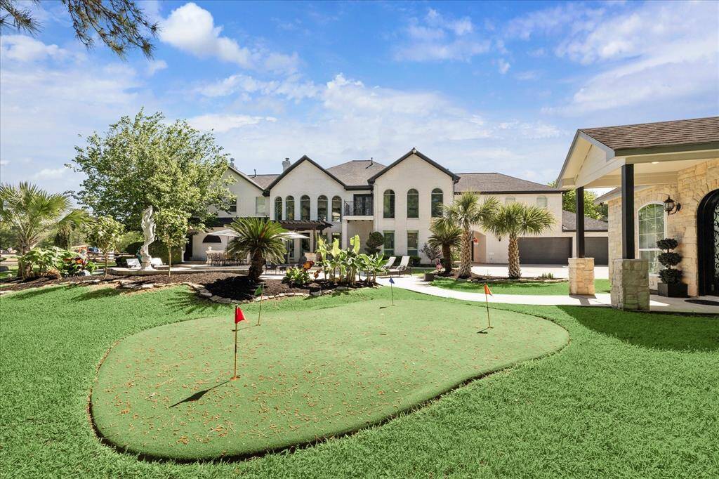 This photo showcases a serene backyard with a sparkling pool and spa, surrounded by lush greenery and tall trees. The elegant stone patio and charming garden statues add a touch of luxury, creating an inviting outdoor oasis.