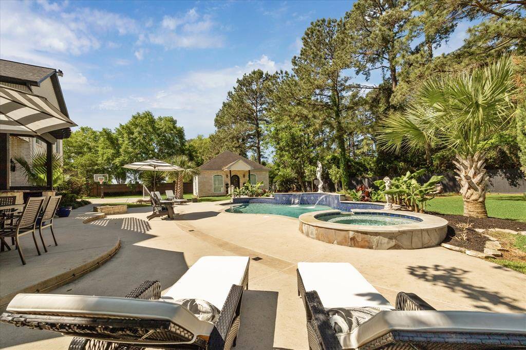This photo showcases a spacious, two-story home with a white exterior, featuring a large backyard with a swimming pool, hot tub, and patio area perfect for outdoor entertaining.