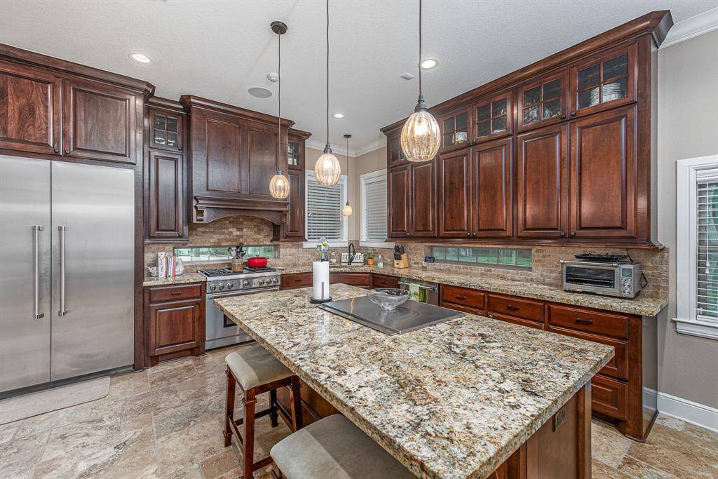 Spacious kitchen with custom-built, stain-grade, soft-close cabinets with undercounter lighting. Counters are granite. Fridge is built in and will convey with sale.