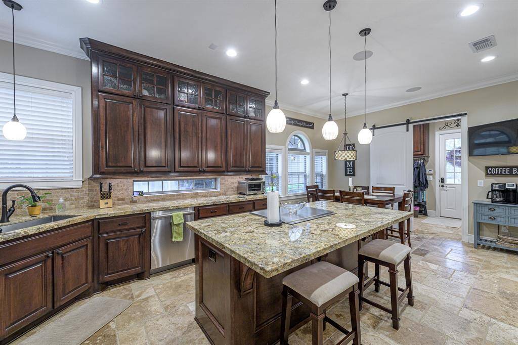 Spacious kitchen with custom-built, stain-grade, soft-close cabinets with undercounter lighting. Counters are granite.