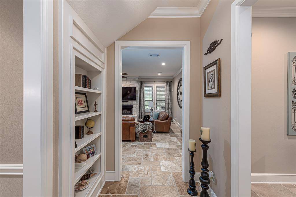 Entryway with custom built-in shelves that serve as a hidden door to a storage closet. To the right lays the office, and the right lays the dining room.