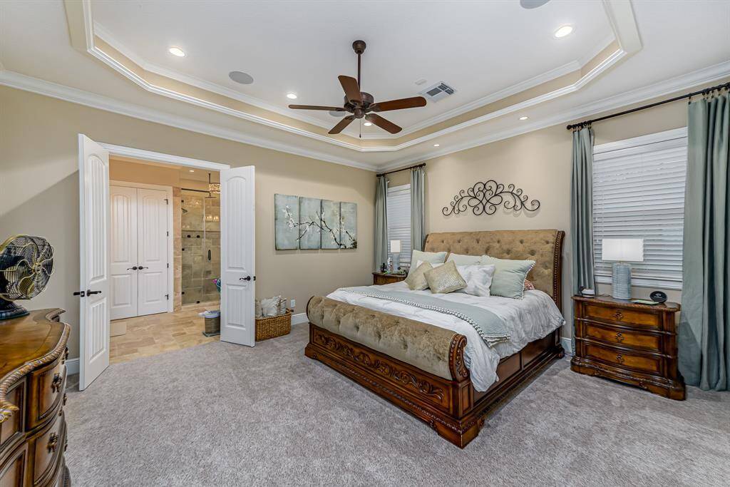 Spacious primary bedroom with tray ceilings.