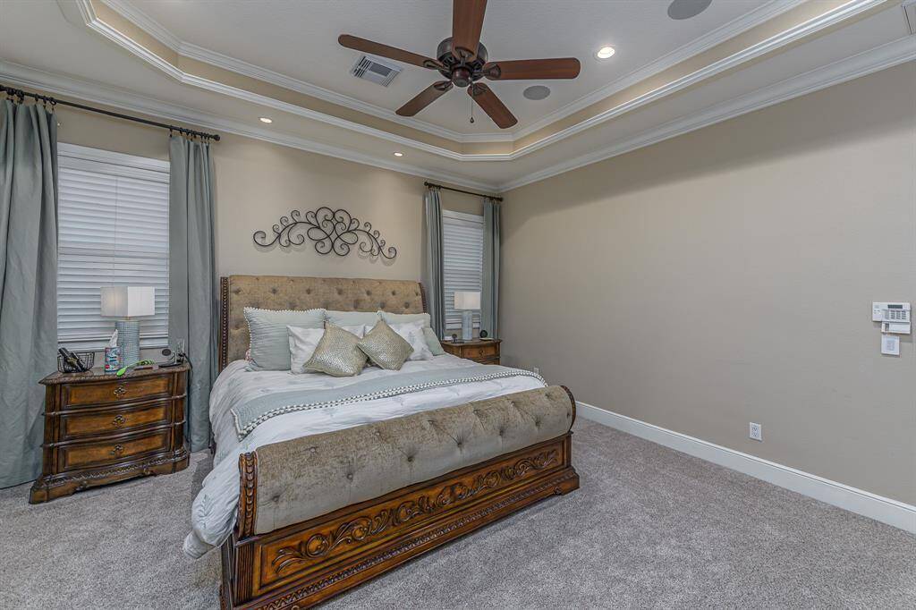 Spacious primary bedroom with tray ceilings.