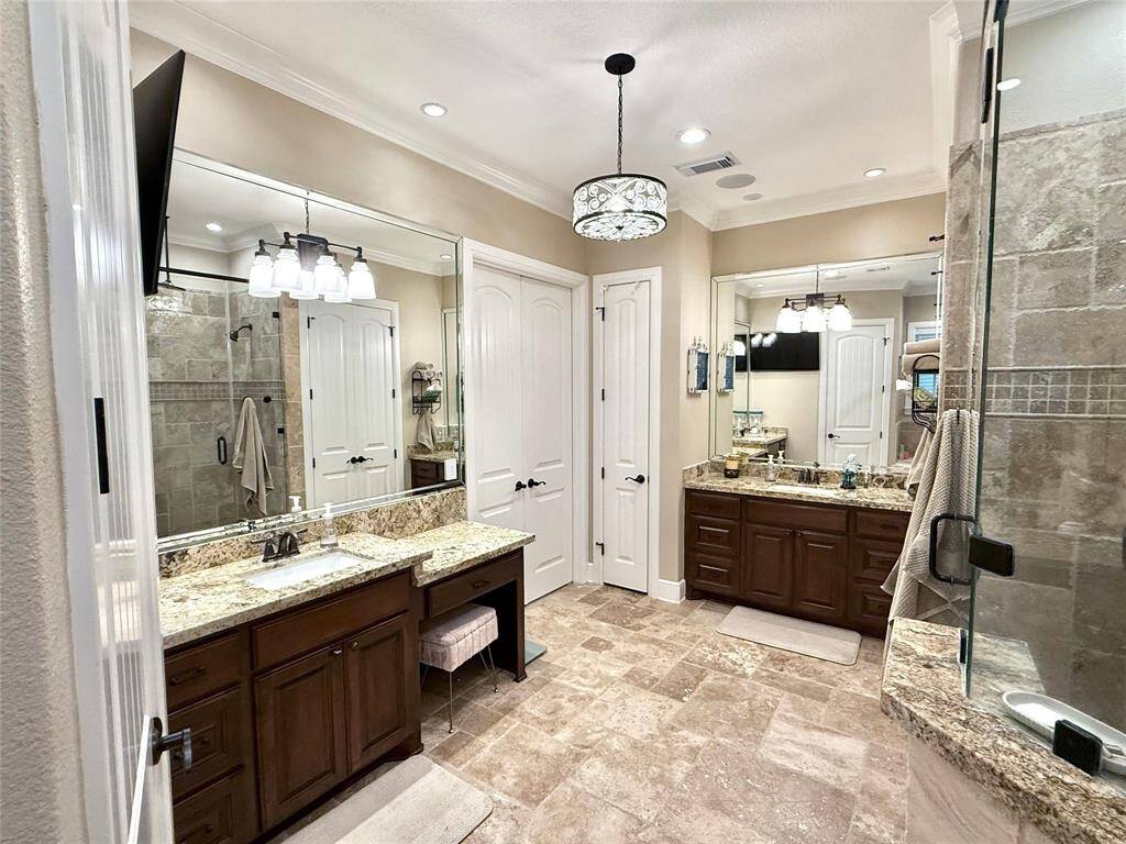 Spacious master bathroom with chandelier, soaking tub, separate stand-alone shower, and separate sinks.