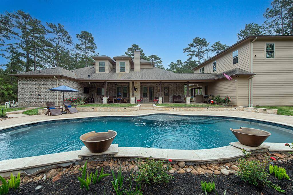 Custom, oversized backyard pool with fire-bowl waterfalls and speakers.