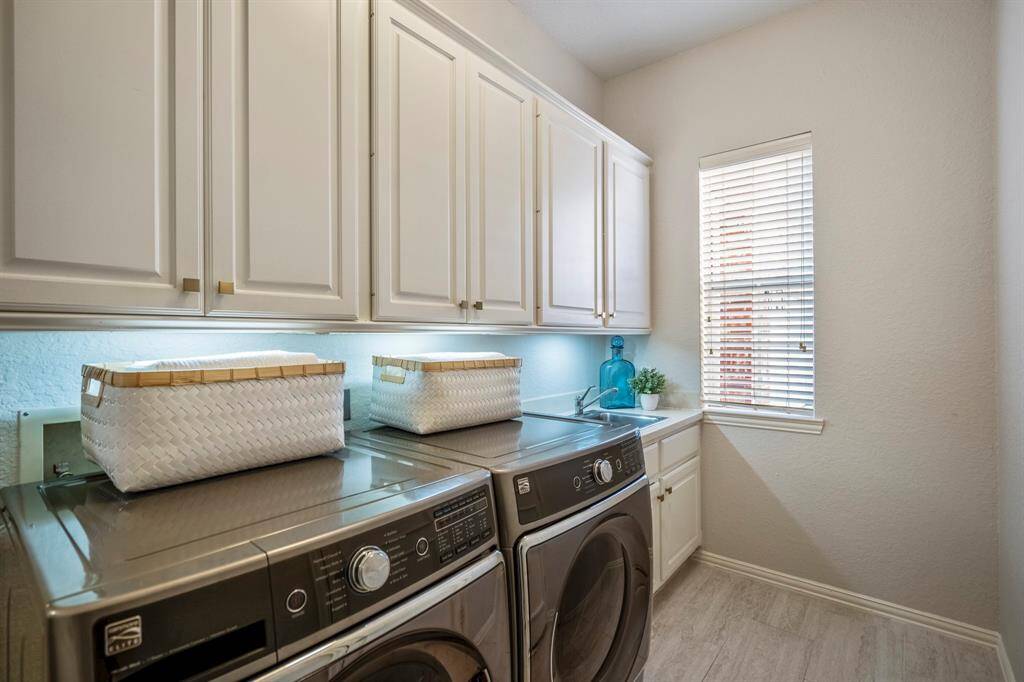 Effortlessly manage chores in the laundry room, featuring ample cabinet storage and a convenient sink.