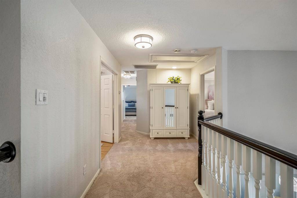 Inviting second-floor hallway with cozy carpeting and elegant railing, offering easy access to upstairs rooms.