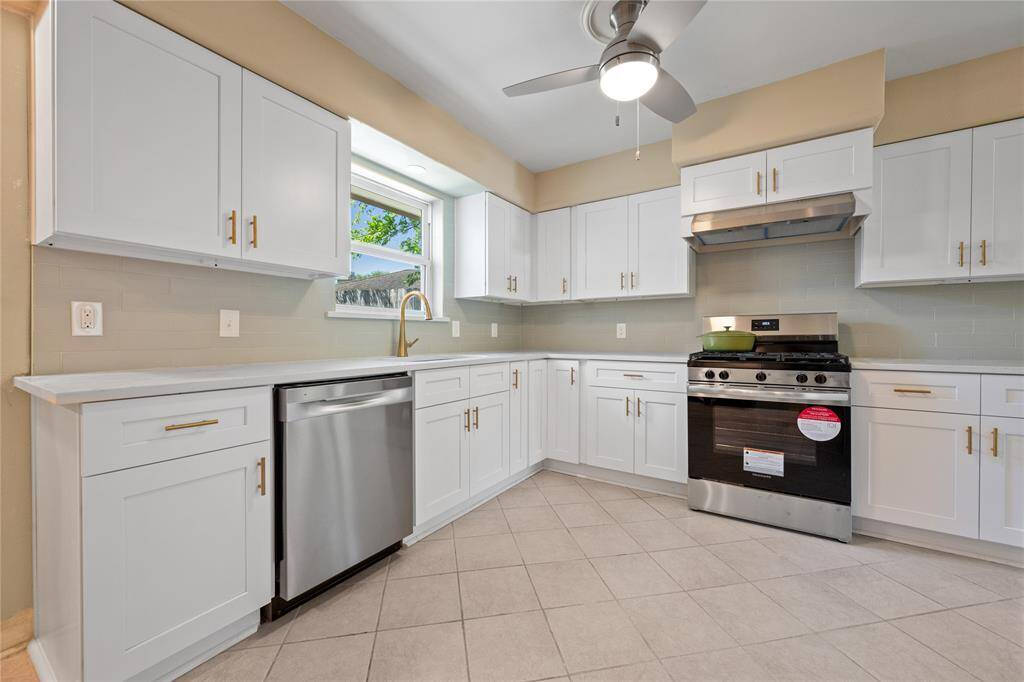 Bright and open kitchen area features neutral-toned tile flooring and flows seamlessly into living area.