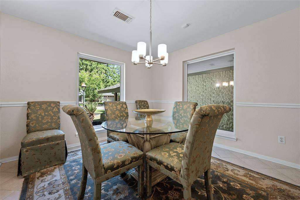 This spacious family room features elegant woodgrain luxury vinyl plank flooring, built-in cabinetry, and a cozy fireplace. It is bright and airy, with ceiling fans and large double doors leading to the outside.
