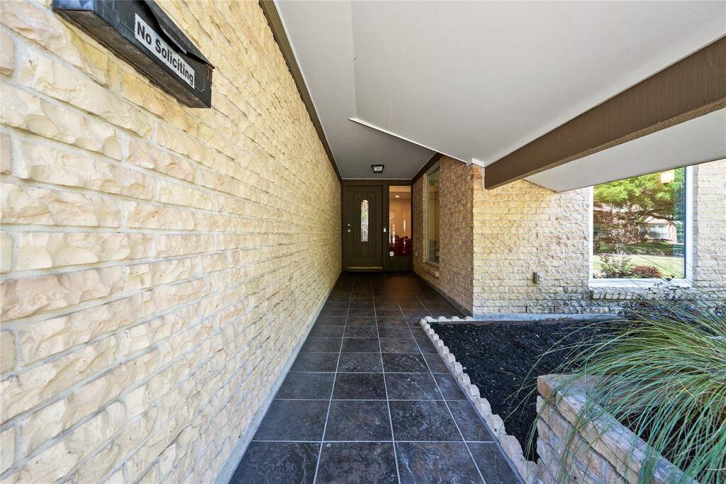 Charming tile-lined covered front entryway with garden space and garden box with fresh mulch.