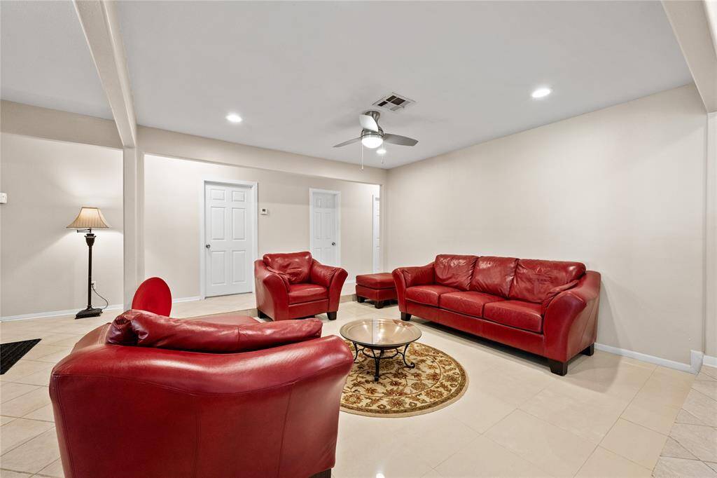 Living room opens seamlessly to a modern kitchen creating a spacious, open-concept feel. Recessed lighting and a ceiling fan add to the comfort and functionality.