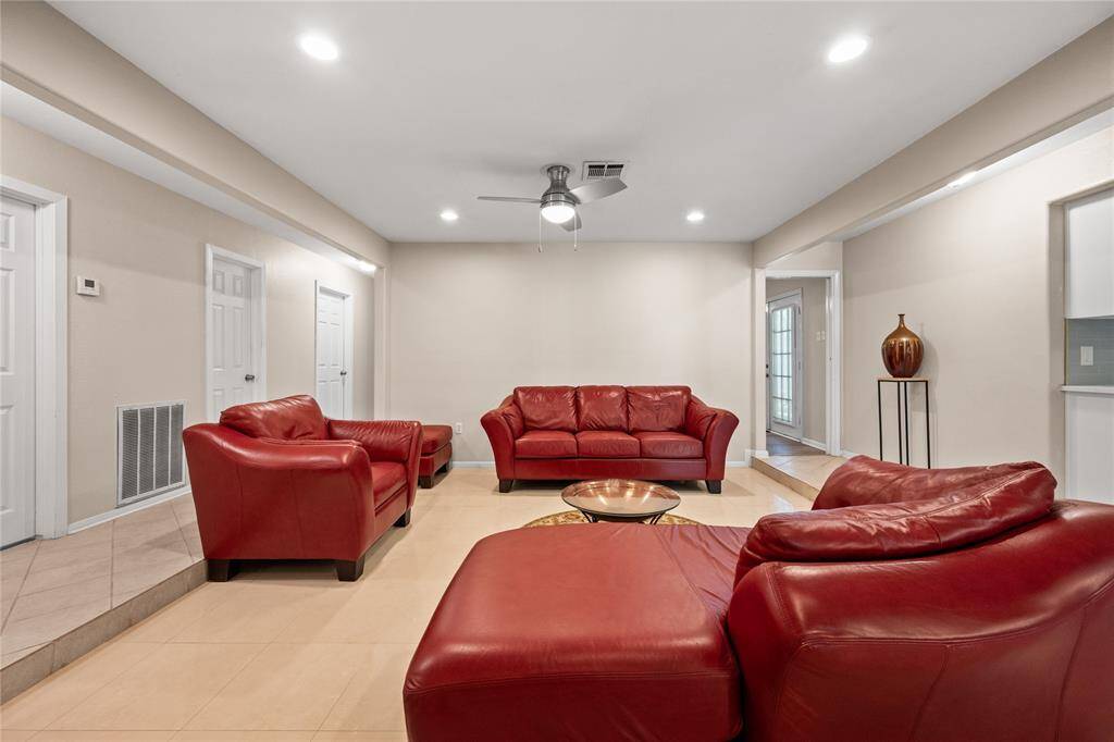 Spacious living room with elegant tile flooring and open layout connects to a dining area, creating a welcoming and functional space for entertaining.