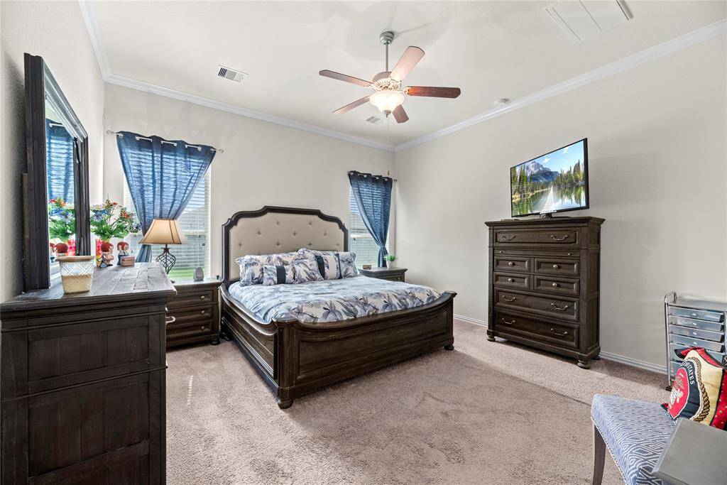 Primary bedroom is spacious with crown molding and plush carpet. All bedrooms in this home have ceiling fans too.