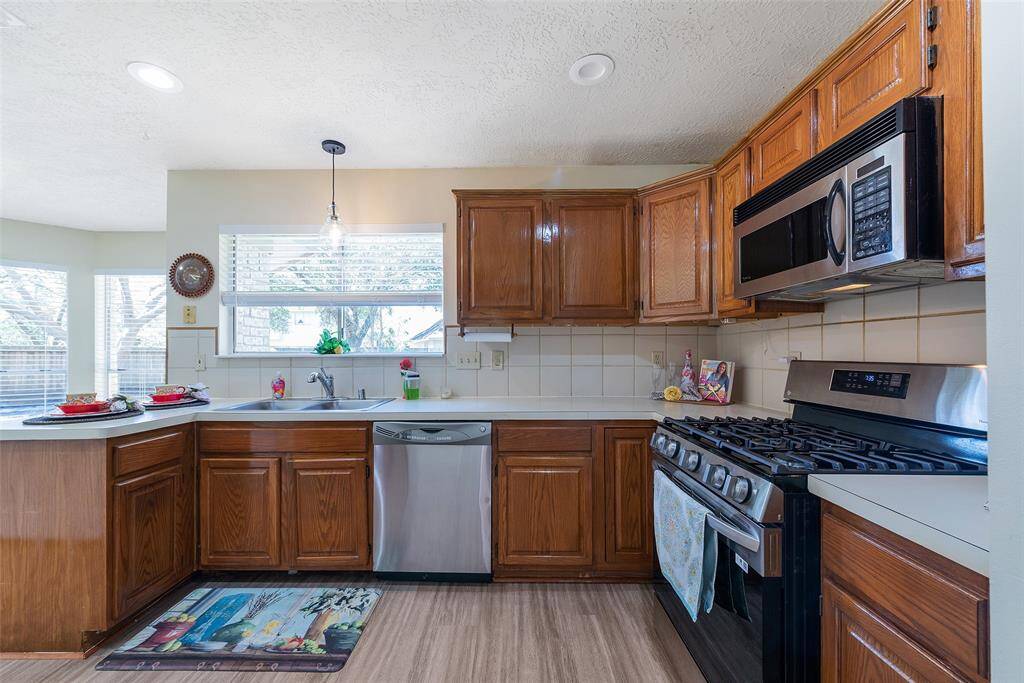 Charming kitchen with gas stove, built-in microwave, stainless steel dishwasher & tile backsplash.