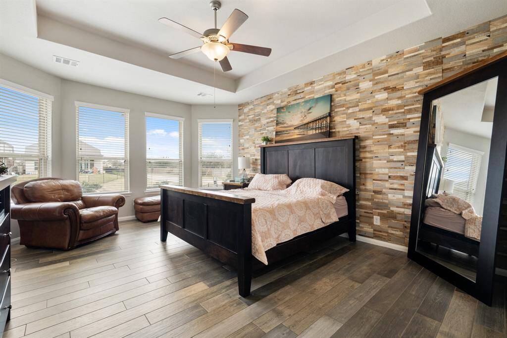 Unwind after a long day in this spacious primary bedroom! Featuring lots of natural light, engineered wood floors, privacy blinds, and a tray ceiling with a ceiling fan.