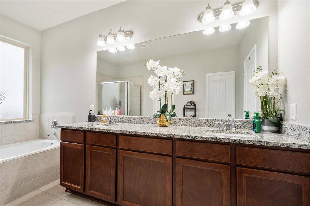 The bathroom includes double sinks, granite countertops, a large mirror, and wooden cabinetry.