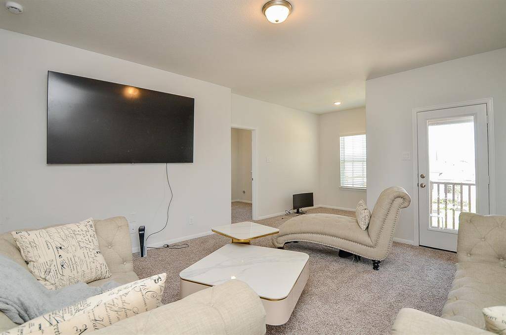 A different perspective of the living room, highlighting a mounted TV and neutral-toned furniture.