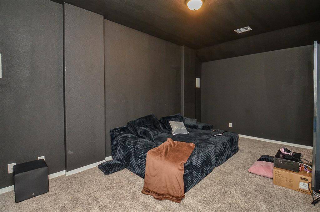 A dedicated theater room with dark walls, theater seating,