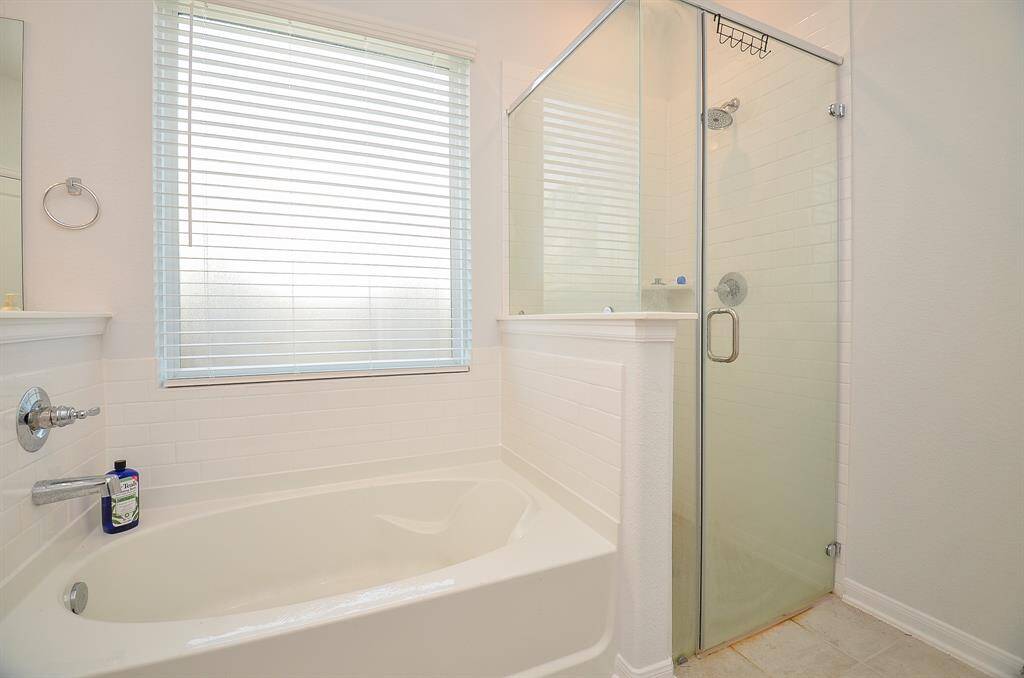 A luxurious bathtub next to a large window, accompanied by a glass-enclosed shower.