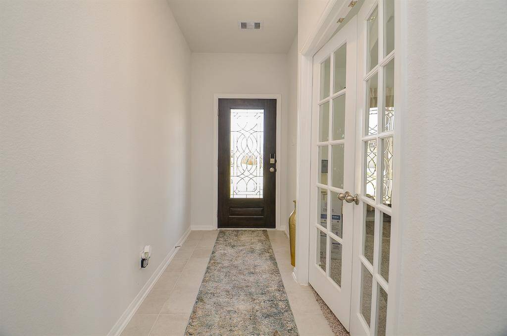 A long entry hallway with light-colored flooring and a view leading toward the main living area.