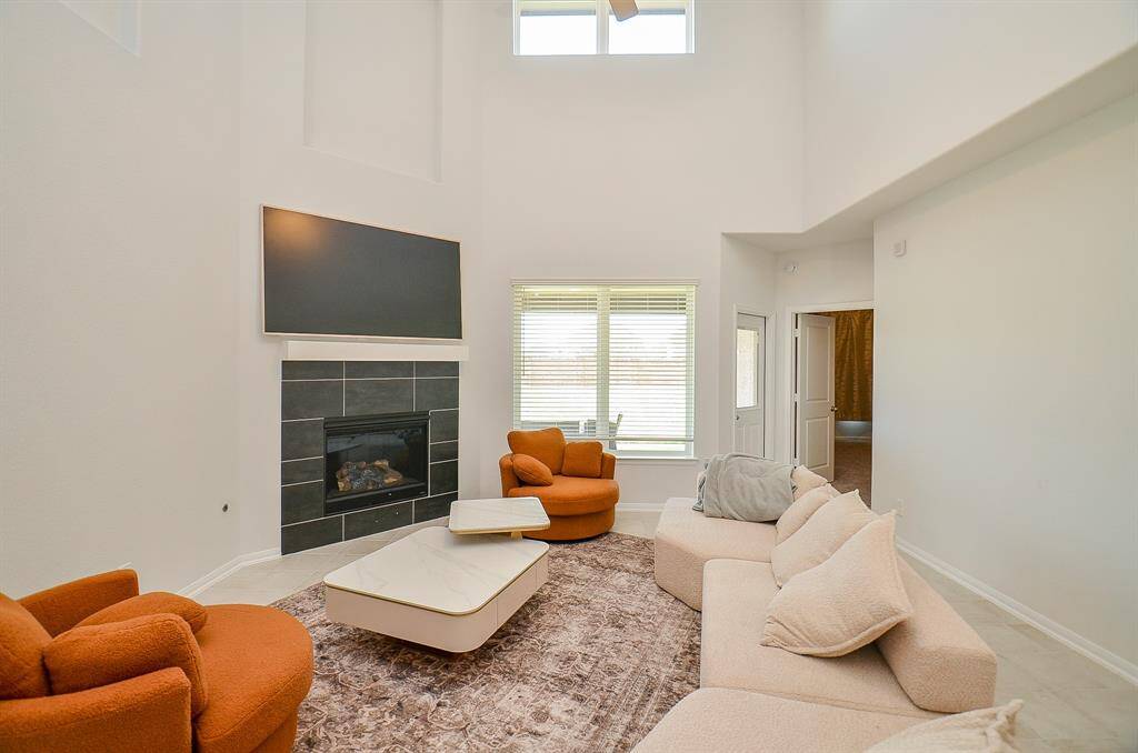 A cozy living room with a fireplace, tall ceilings, and stylish furnishings.