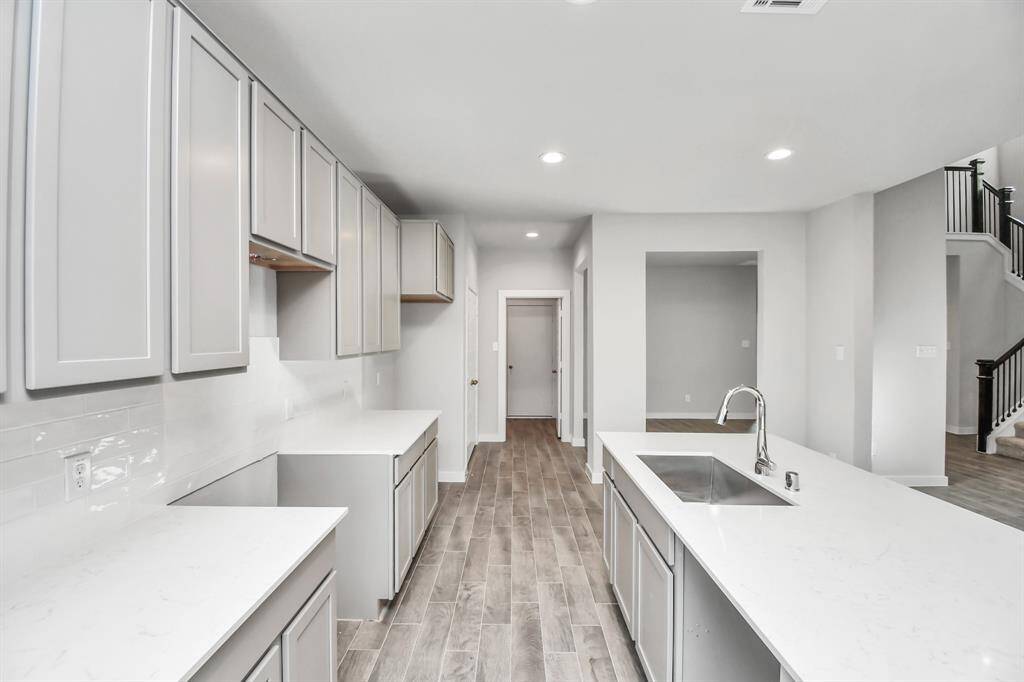 Step into the dream kitchen you've always wanted! This generously spacious culinary haven features a massive granite island, high ceilings, soft-close cabinets, granite countertops, stainless steel appliances (To be Installed), a sleek tile backsplash, and recessed lighting. Sample photo of completed home with similar floor plan. Actual colors and selections may vary.