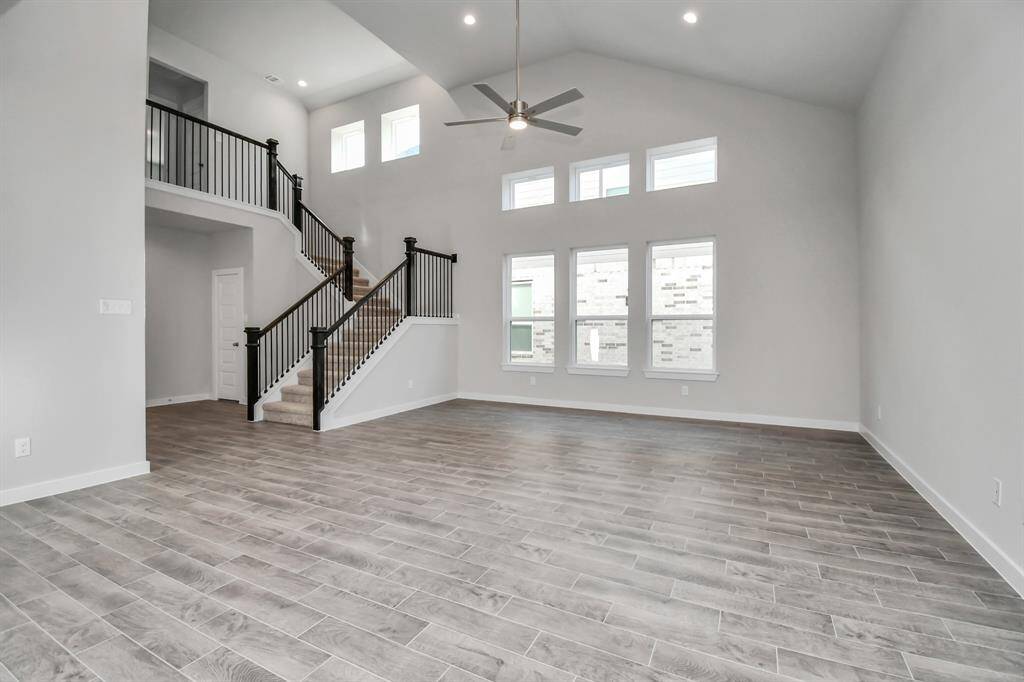 Bring your family and guests together in your delightful living room! Boasting lofty high ceilings, recessed lighting, a ceiling fan, custom paint, beautiful floors, and expansive windows that flood the space with ample natural light throughout the day. Sample photo of completed home with similar floor plan. Actual colors and selections may vary.
