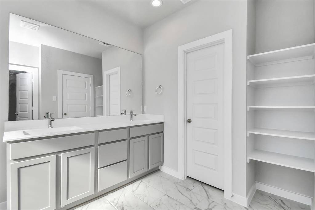 Primary bedroom walk-in closet that epitomizes luxury and practicality. This generously sized space features built-in shelving, offering abundant room for impeccable organization. High ceilings and recessed lighting create a bright and welcoming ambiance. Sample photo of completed home with similar floor plan. Actual colors and selections may vary.