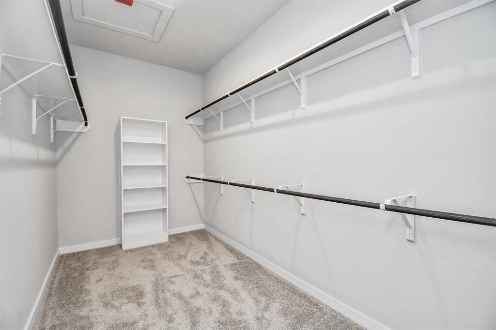 Primary bedroom walk-in closet that epitomizes luxury and practicality. This generously sized space features built-in shelving, offering abundant room for impeccable organization. High ceilings and recessed lighting create a bright and welcoming ambiance. Sample photo of completed home with similar floor plan. Actual colors and selections may vary.