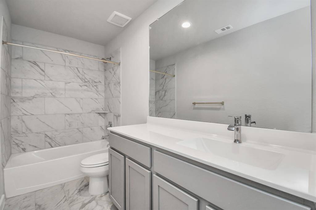 Sophistication within the secondary bathroom, where tile flooring perfectly complements a bath/shower combo surrounded by tile. Light wood cabinets, and a beautiful light countertop elevate the space, creating a truly inviting ambiance. Sample photo of completed home with similar floor plan. Actual colors and selections may vary.