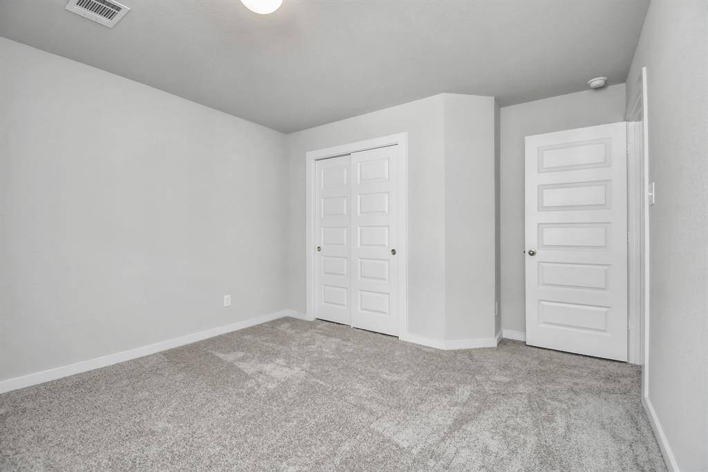 Secondary bedrooms showcase 5-panel doors adorned with modern hardware, large windows enhanced by privacy blinds, and spacious closets featuring sleek and contemporary finishes. Sample photo of completed home with similar floor plan. Actual colors and selections may vary.