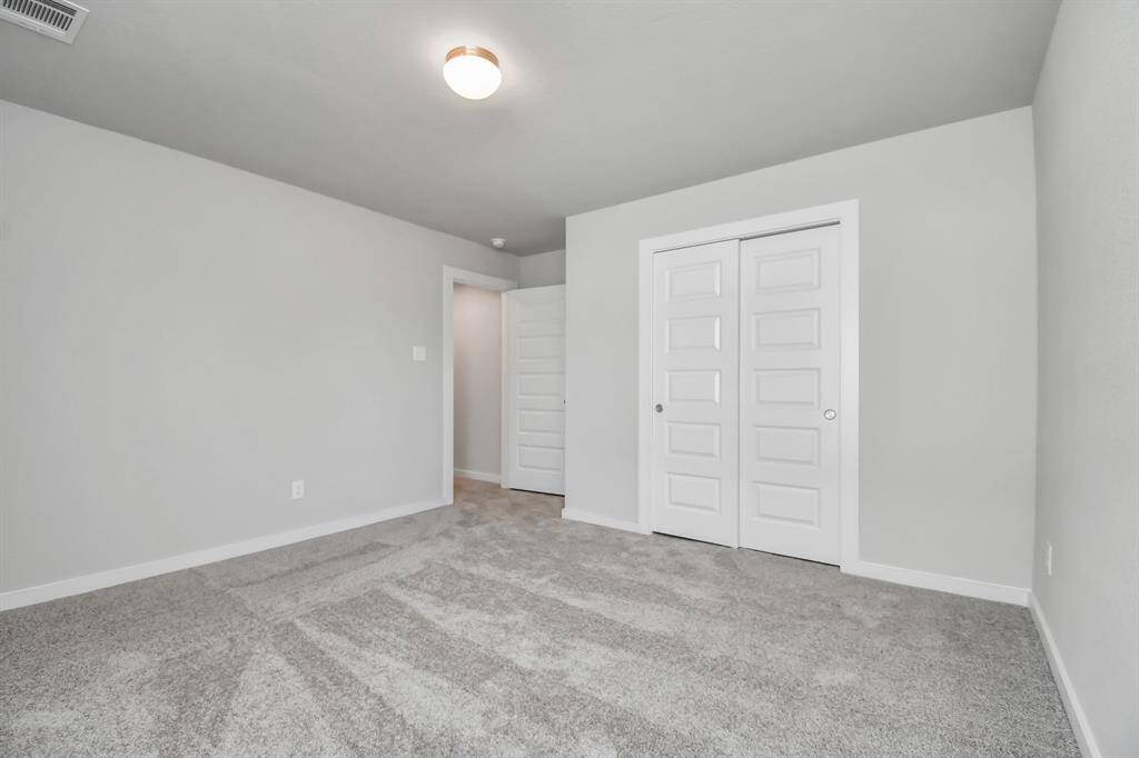 Secondary bedrooms showcase 5-panel doors adorned with modern hardware, large windows enhanced by privacy blinds, and spacious closets featuring sleek and contemporary finishes. Sample photo of completed home with similar floor plan. Actual colors and selections may vary.