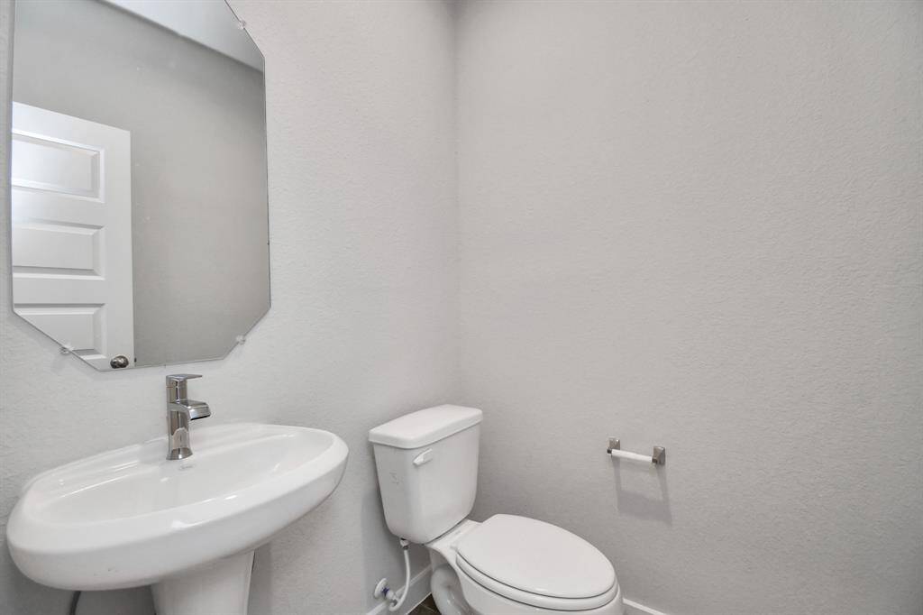 Experience modern elegance in this charming half bathroom, boasting a sophisticated 5-panel door, upgraded pedestal sink and contemporary hardware. The warm paint palette bathes the area in a welcoming glow, creating a bright and inviting atmosphere. Sample photo of completed home with similar floor plan. Actual colors and selections may vary.