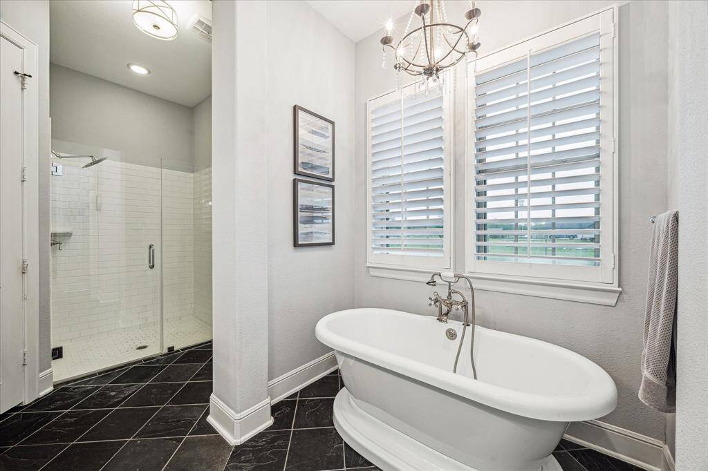 LUXURIOUS STANDUP SEAMLESS SHOWER SEPARATE FROM THE ELEGANT AND RELAXING SOAKING TUB WITH POLISHED CHROME FIXTURES AND CUSTOM SHUTTERS FOR PRIVACY AND LIGHT