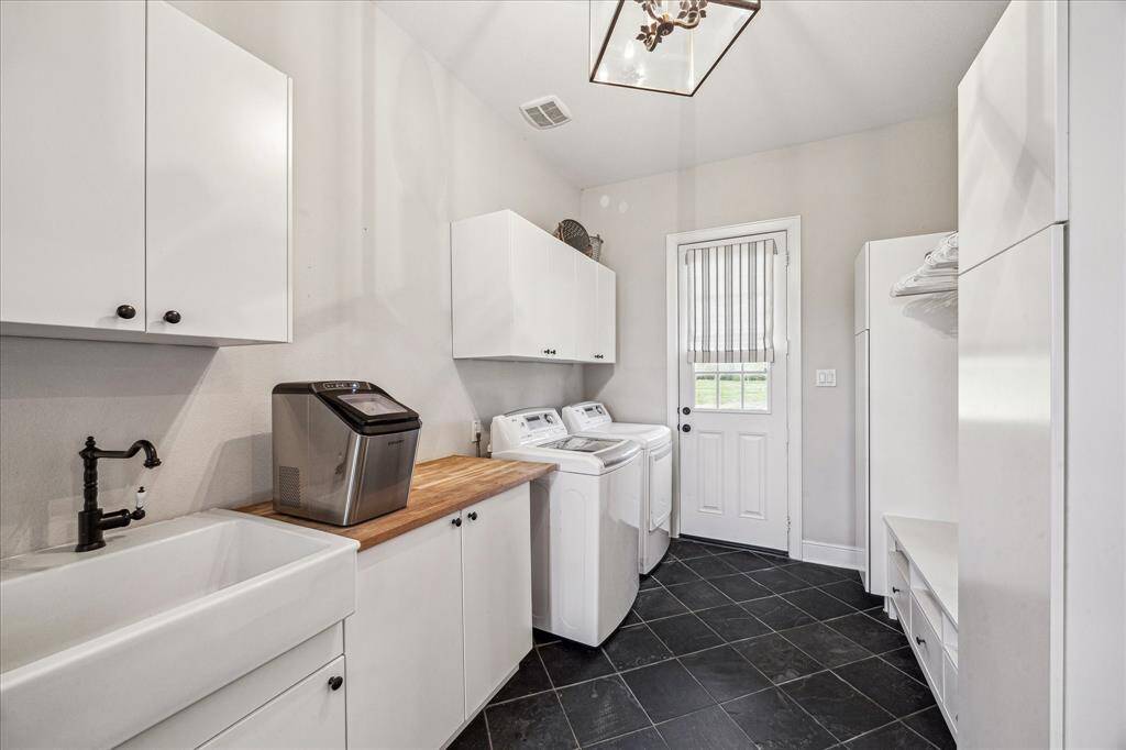 UTILITY ROOM FEATURES APRON SINK, UPGRADED FAUCET, PLENTY OF CABINET STORAGE,BUTCHER BLOCK COUNTER FOLDING TABLE, CLOTHING RACKS AND STORAGE TO THE RIGHT, SLATE FLOORING- THE DOOR GOES OUT TO THE LEFT SIDE OF THE HOME