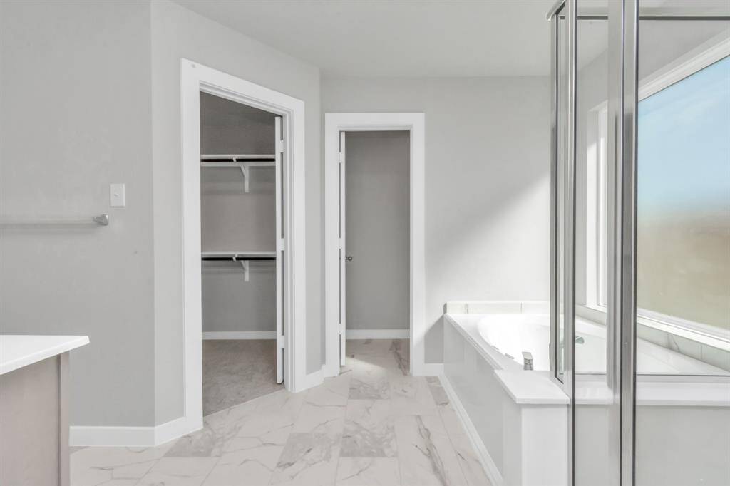 Extra glimpse into the primary bathroom featuring a spacious walk-in closet, adding an extra touch of convenience and luxury to your daily routine. Sample photo of completed home with similar floor plan. As-built interior colors and selections may vary.