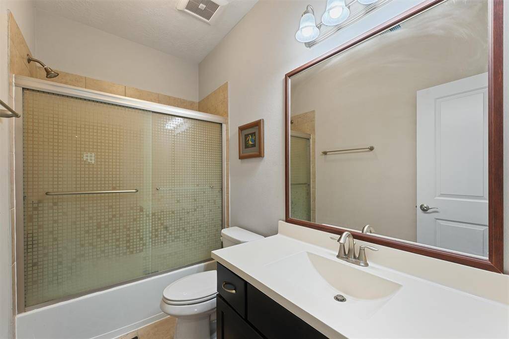 Secondary bathroom on 2nd floor featuring a bathtub with a sliding glass door, a modern vanity with a large mirror, and overhead lighting.