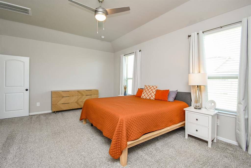 Primary bedroom with custom ceiling fan, blinds, and plenty of natural light