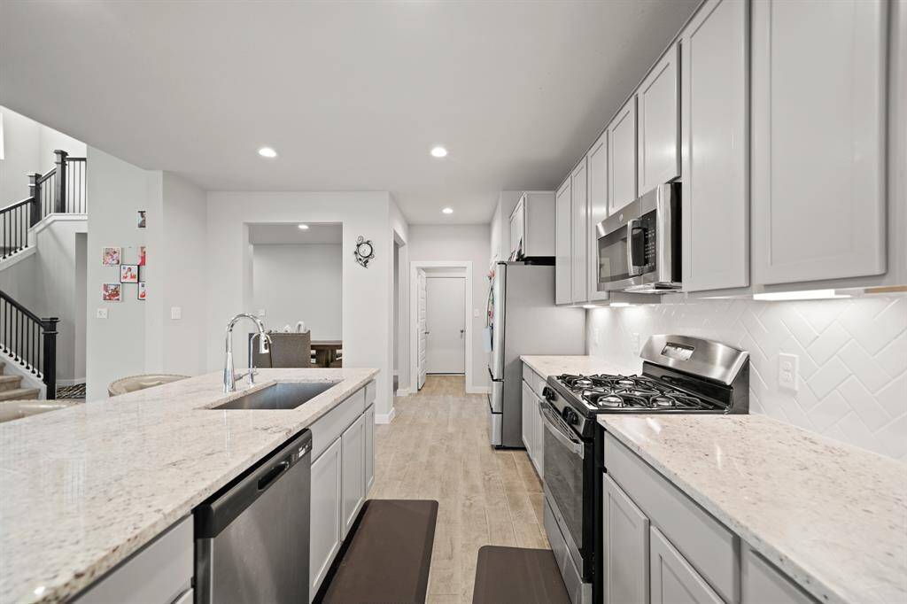 Quartz countertops paired with a coordinating tiled backsplash not only provide a durable and elegant surface for food preparation but also add a touch of luxury and sophistication to the kitchen.