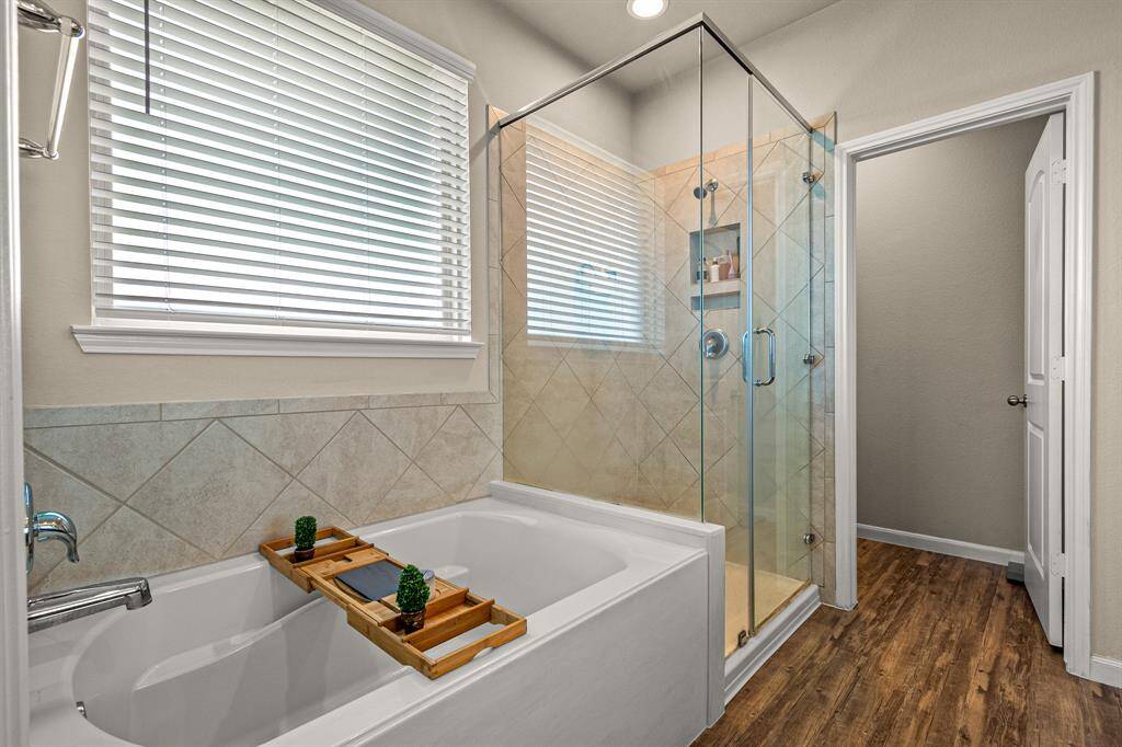 Luxurious primary ensuite featuring a spacious soaking tub and elegant glass-enclosed shower, perfect for relaxation and rejuvenation.